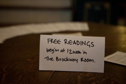 A sign on the entrance table at Conway Hall telling people that Free Readings will begin at midday in the Brockway Room