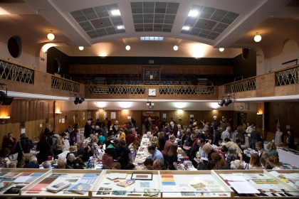 A view from the stage at Conway Hall ofa busy Small Publishers Fair, early on a winter's evening - lights in Conway Hall twinkling.