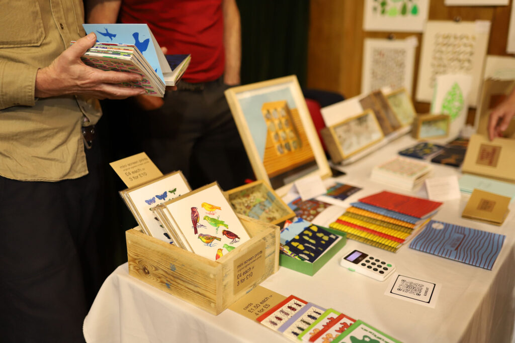 Table covered in colourful small books and postcards by John Dilnot.